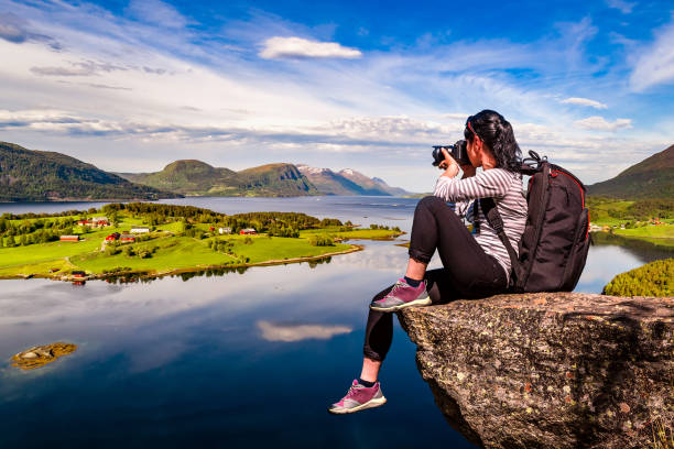 Nature photographer tourist with camera shoots while standing on top of the mountain. Beautiful Nature Norway Lofoten archipelago.